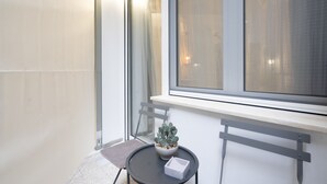 A small balcony with a potted plant, a chair, and a table. - Loft Suite In Syntagma By Metro | Best Location (Athens)