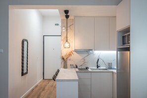 Une cuisine moderne avec des armoires blanches, un pare-feu en marbre et un réfrigérateur en acier inoxydable.
