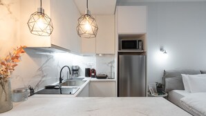 A modern kitchen with a marble countertop, stainless steel appliances, and pendant lighting. - Loft Suite In Syntagma By Metro | Best Location (Athens)