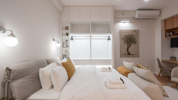 A modern bedroom with a large bed, a bedside table, a chair, a wardrobe, and a desk with a chair. - Loft Suite In Syntagma By Metro | Best Location (Athens)