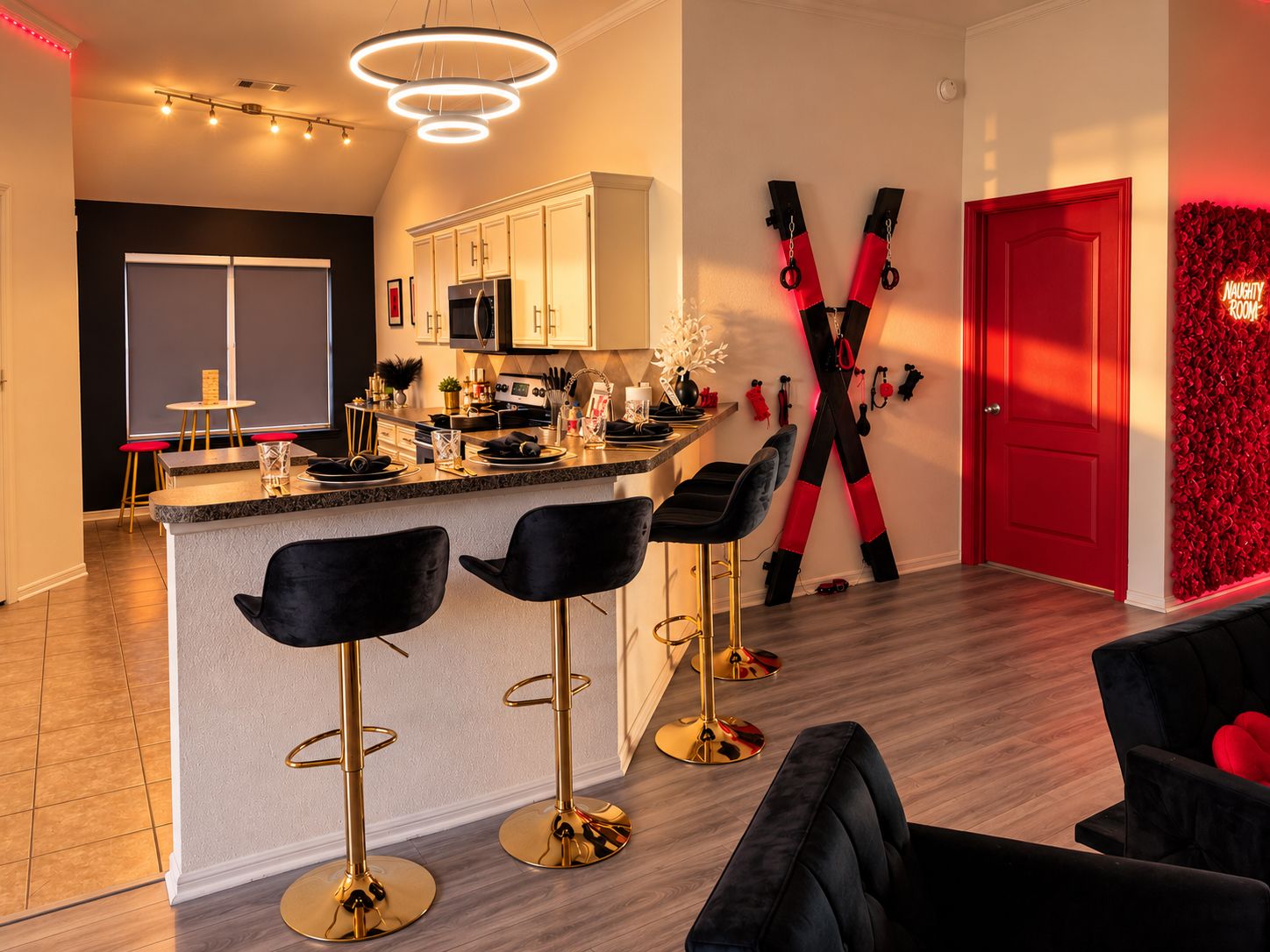 A modern kitchen with a central island, bar stools, and a red door.