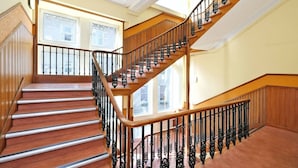 Una imponente escalera de madera con barandillas de hierro negro que conduce a un piso superior.