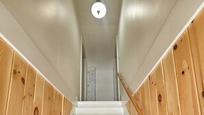 Un escalier aux marches blanches et aux murs en bois, menant à une porte située en haut.