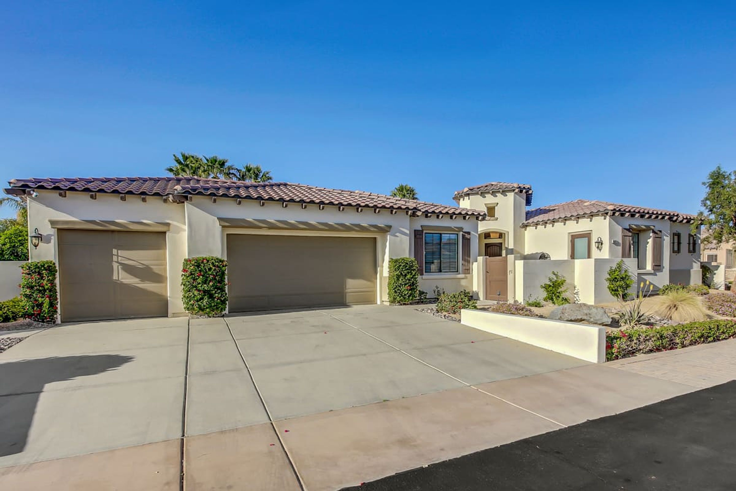 A two-story house with a tiled roof, a garage, and a landscaped front yard.
