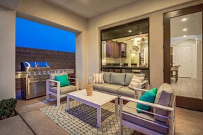 An outdoor patio area with a grill, seating, and a view into the kitchen.
