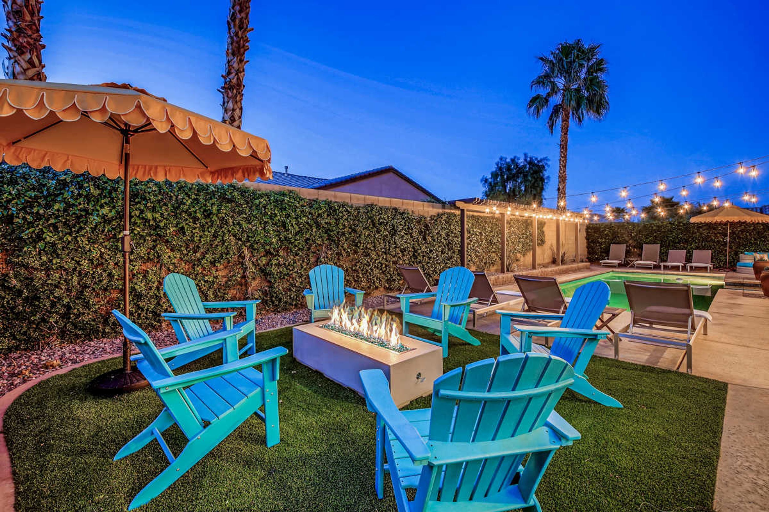 An outdoor seating area with Adirondack chairs, a fire pit, and a pool.