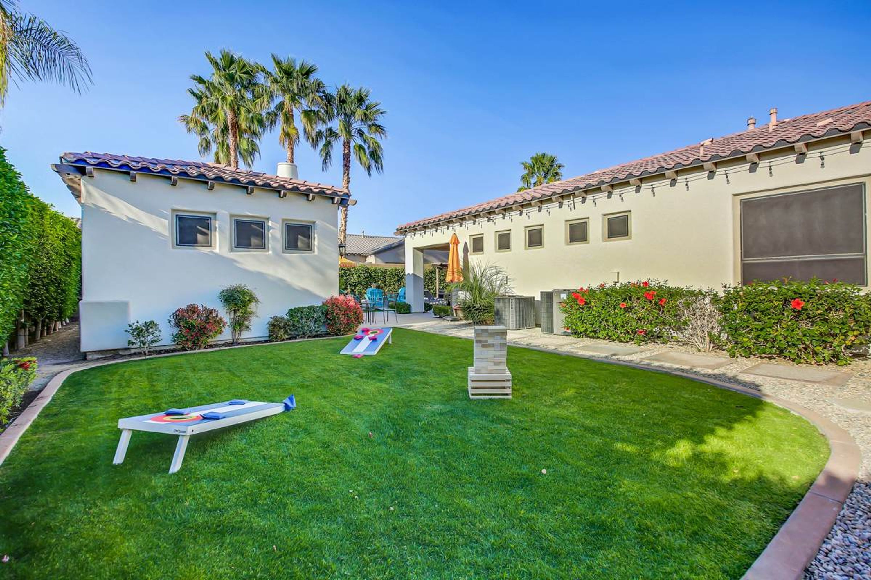 A well-maintained lawn with a sun lounger, a stone pillar, and a building with a tiled roof and large windows.