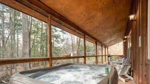 A hot tub on a wooden deck with a view of a forest.