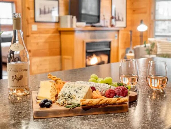 A charcuterie board with cheese, grapes, and a bottle of wine on a kitchen counter.