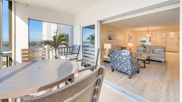 A spacious balcony with a dining table and chairs, a sofa, and a patterned armchair.