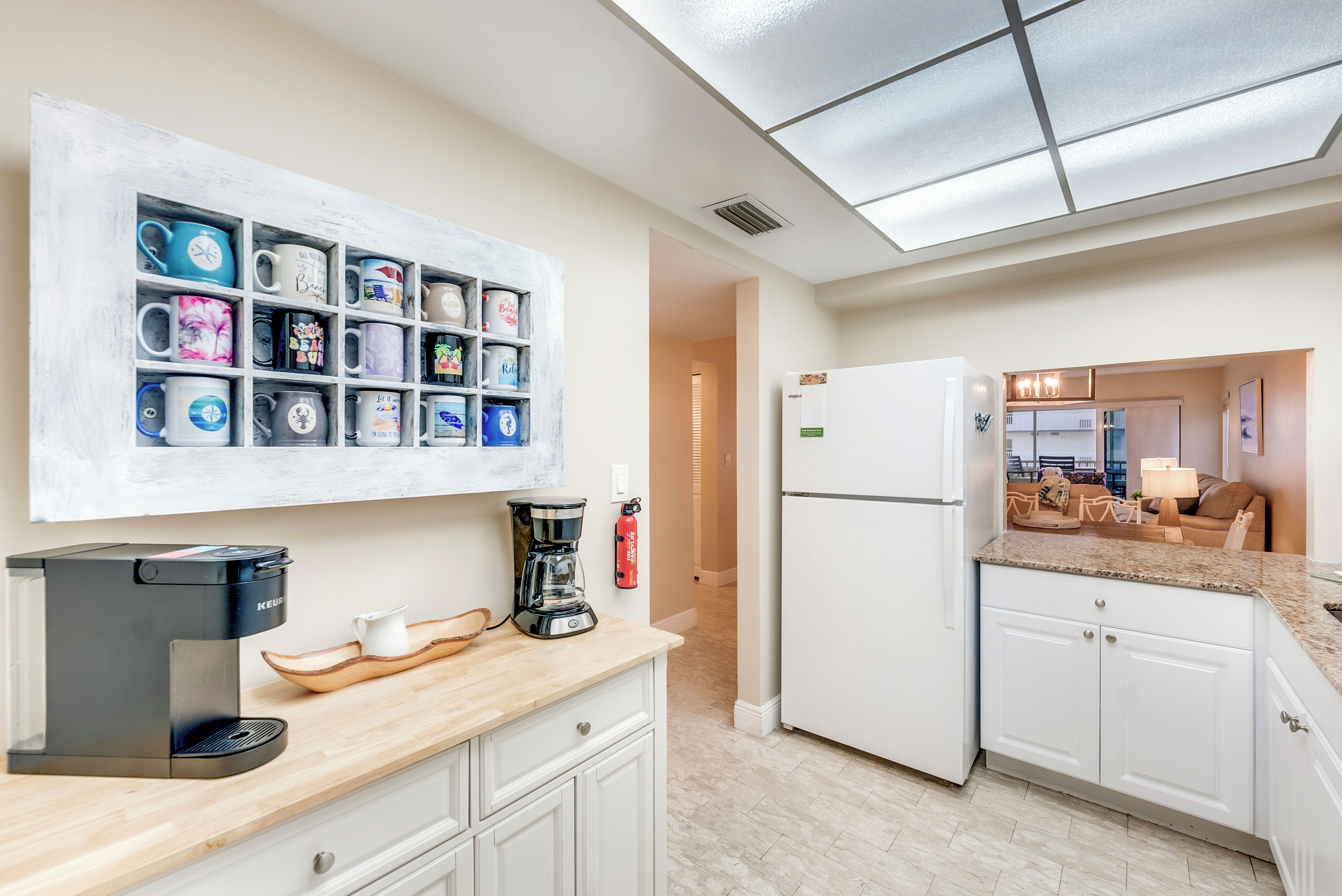Une cuisine moderne équipée d’une machine à café, d’un réfrigérateur et d’un porte-tasses fixé au mur.