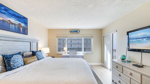 A bedroom with a large bed, a desk, and a TV.