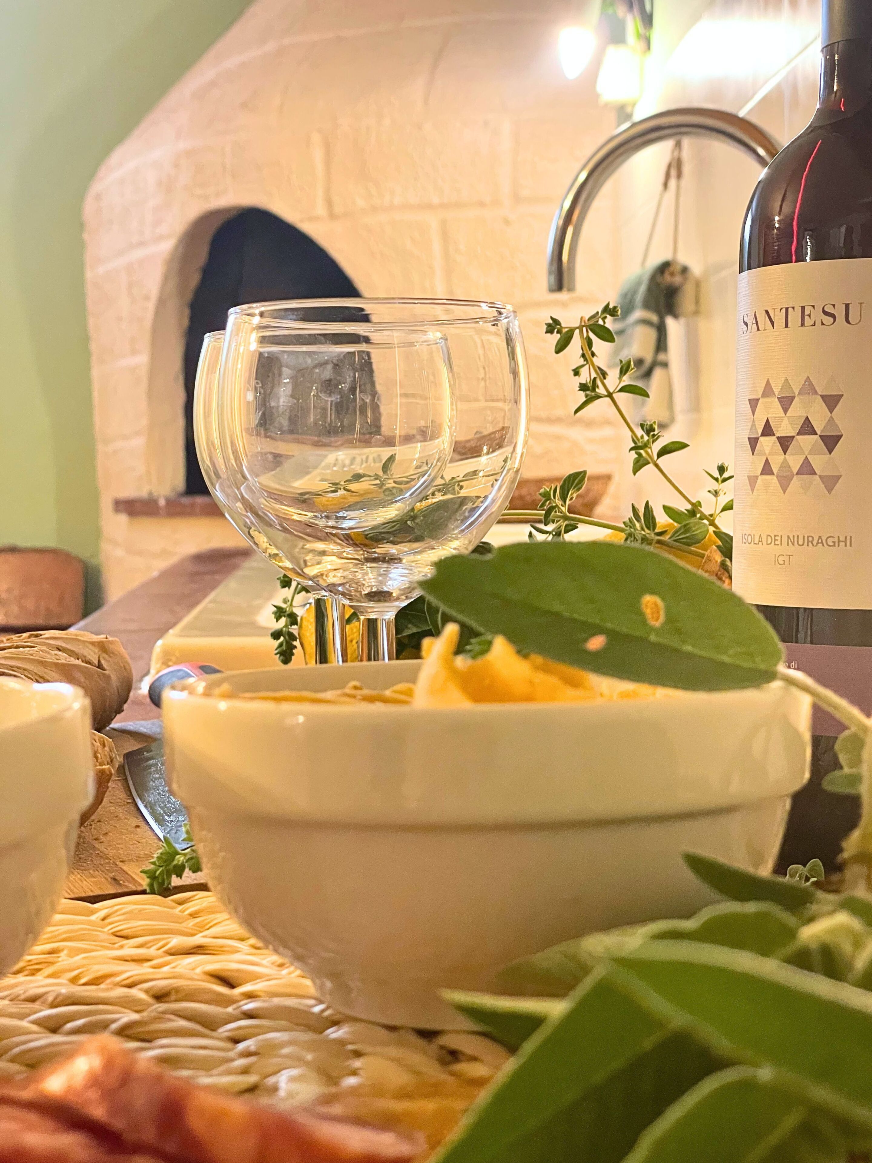 Una botella de vino, una copa y un bol con comida sobre una mesa.