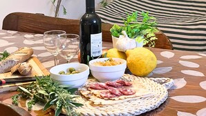 A dining table with a bottle of wine, glasses, a plate of food, and a bowl of olives.
