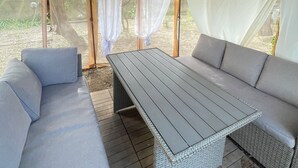 A covered outdoor seating area with a table and two sofas.