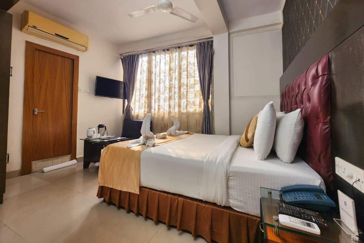 A hotel room with a bed, a desk with a computer, a telephone, and a television.