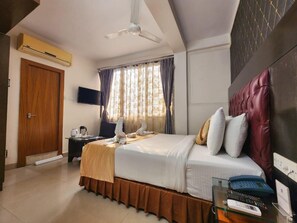 Ein Hotelzimmer mit einem Bett, einem Schreibtisch mit Computer, Telefon und Fernseher.