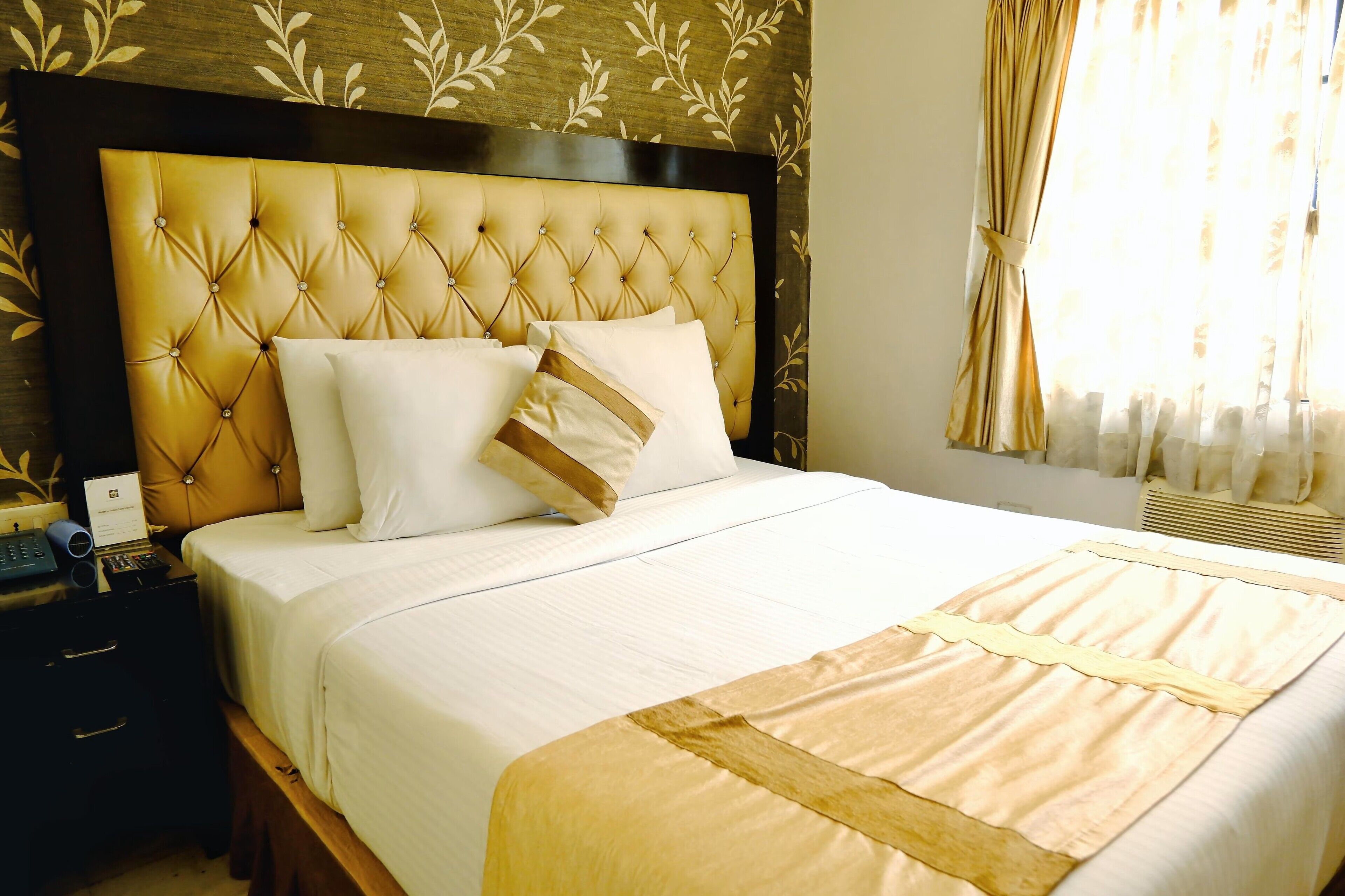 A neatly made bed with a tufted headboard, white bedding, and a beige accent.