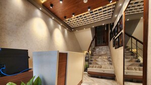 Um interior moderno com teto de madeira, escadaria de mármore e TV de tela plana sobre suporte de madeira.