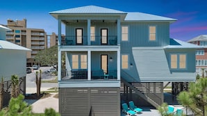 A multi-story building with balconies, a pool area with lounge chairs, and a staircase. - Azure Horizon Beachfront Charm in Gulf Shores (Gulf Shores)