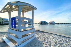 Une plage avec une tour de surveillance pour les sauveteurs et une jetée qui s’avance dans l’eau.