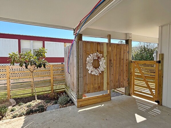 Un espacio al aire libre cubierto con un portón de madera, un adorno de guirnalda y un pequeño árbol.