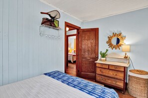 A bedroom with a bed, dresser, mirror, and wall-mounted shelf. - Seaworthy - Dog Friendly, Updated Classic Cottage with Bonus Space! (Topsail Beach)