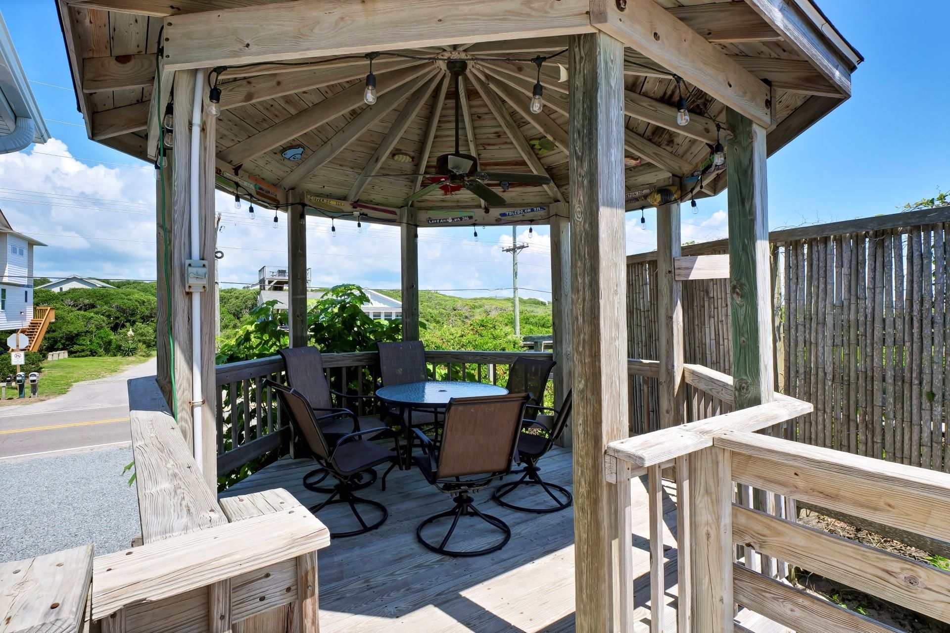 Un kiosque en bois avec une table et des chaises, entouré d’une terrasse en bois.