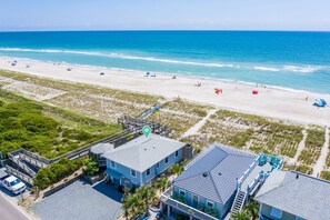 A coastal property with a beach view, a parking area, and a building with a balcony.