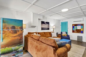 A modern living room with a sofa, a coffee table, and artwork on the walls. - Seaworthy - Dog Friendly, Updated Classic Cottage with Bonus Space! (Topsail Beach)