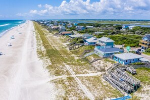 A coastal residential area with beachfront properties, including houses with blue exteriors and a beach with umbrellas.
