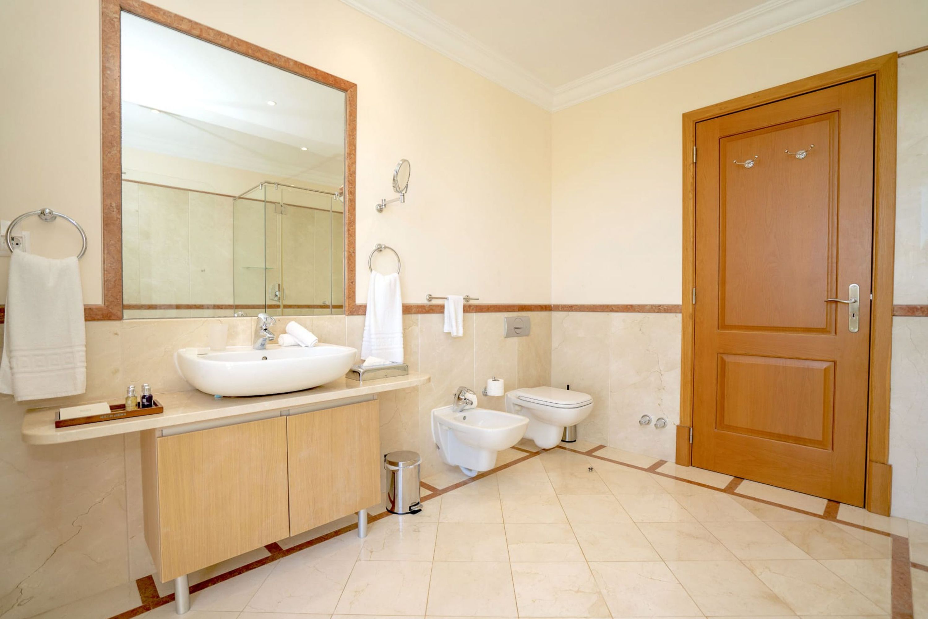 A modern bathroom with a large mirror, a sink, a bidet, and a toilet.