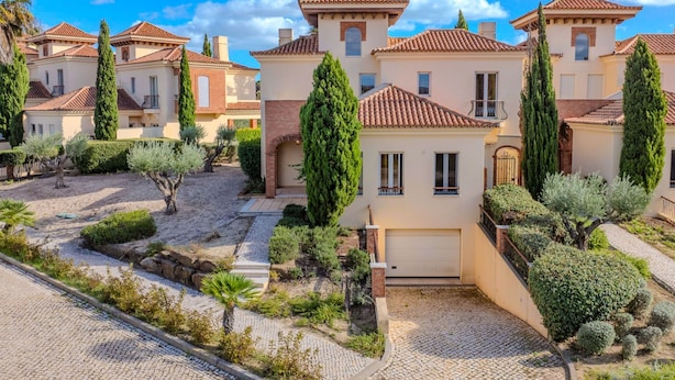 Un barrio residencial con varias casas, cada una con techo de tejas y rodeada de jardines y árboles bien cuidados.