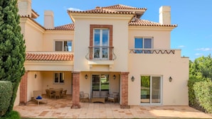 Una casa de dos pisos con un patio, un balcón y una puerta corredera de vidrio.