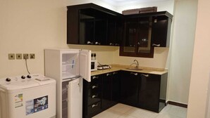 A compact kitchen with a refrigerator, microwave, and sink. - luluat althuraya serviced apartmints 8 (Riyadh)