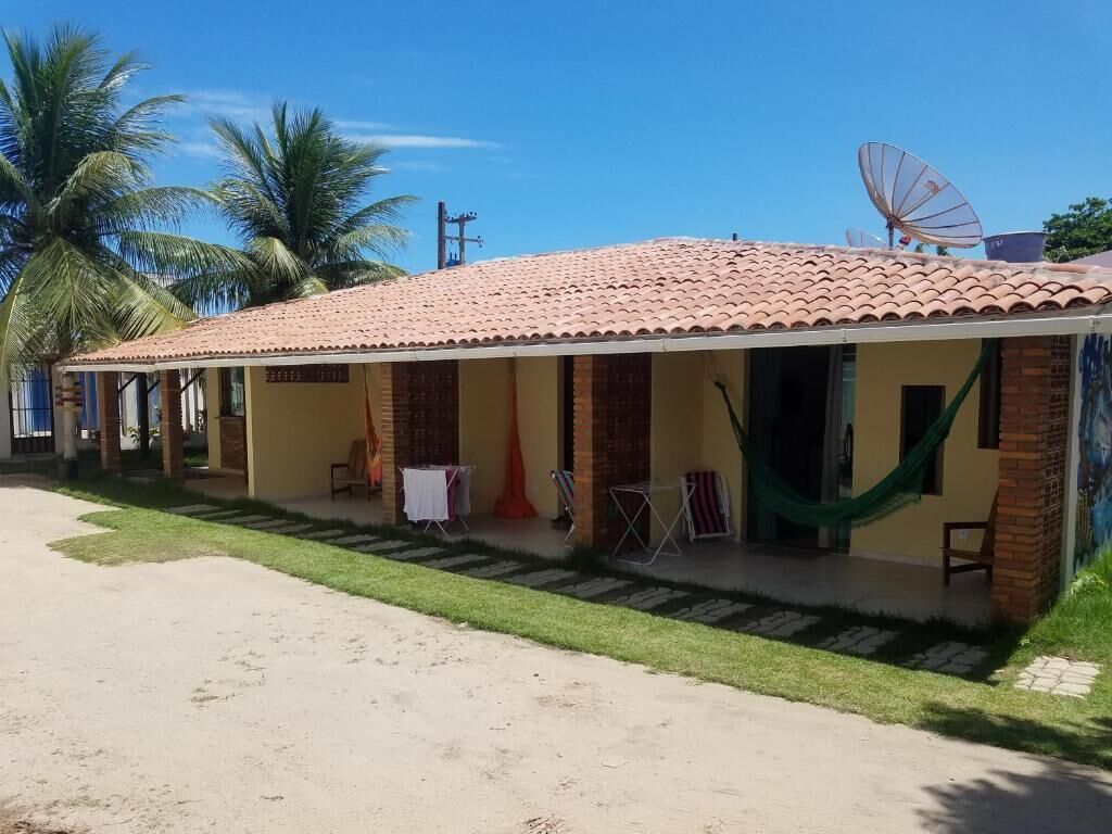 Um edifício de dois andares com telhado de cerâmica, varanda coberta e antena parabólica.