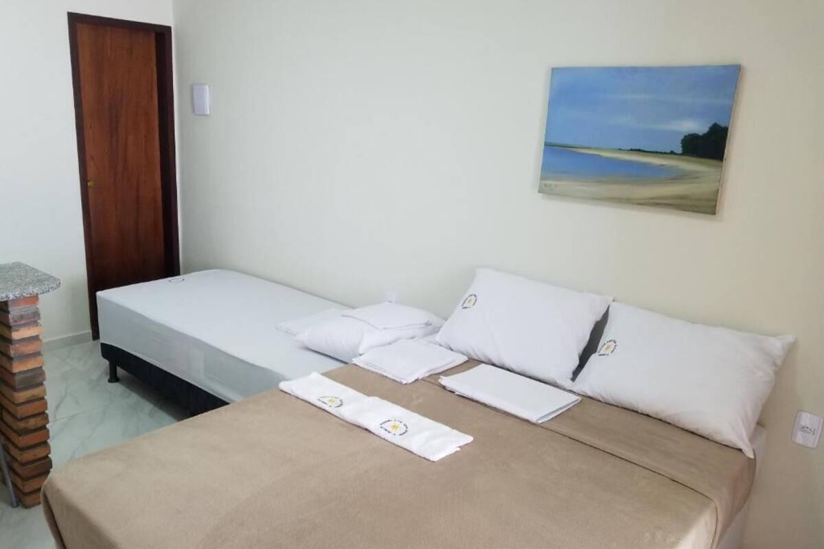 Un dormitorio con una cama, una puerta de madera, una mesita pequeña y un cuadro en la pared.