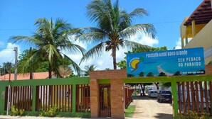 Entrada cerrada con un letrero que indica Pousada Areaal Barra Grande, con vista a la playa y un número de contacto.