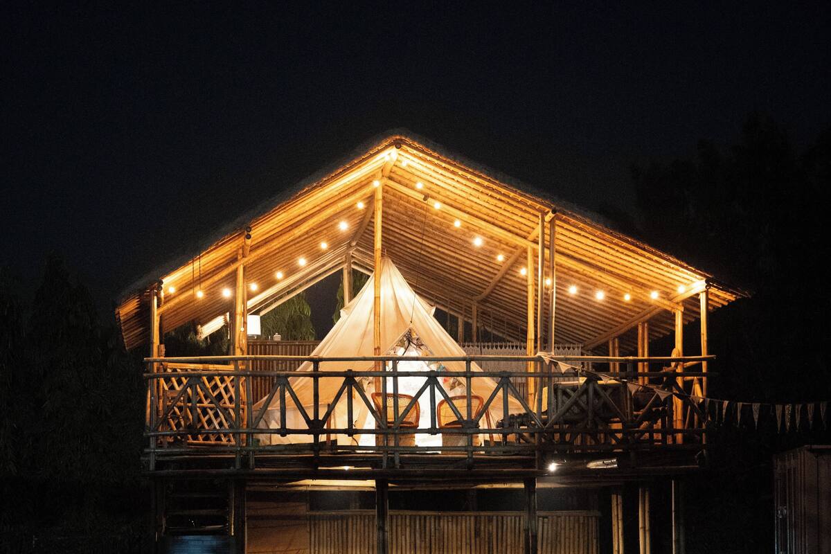 A large, well-lit tent with a wooden frame and a covered walkway.