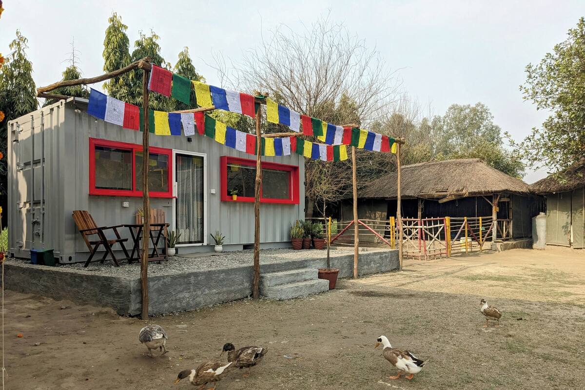 A rustic building with a thatched roof, a small porch, and colorful prayer flags.