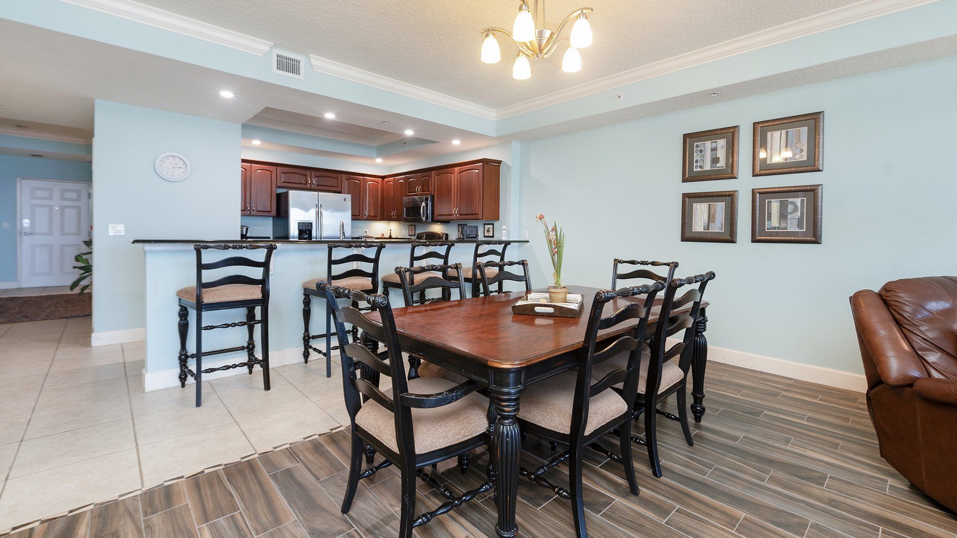 A spacious kitchen with dark wooden cabinets, a central island, and a dining area with a large wooden table and chairs.