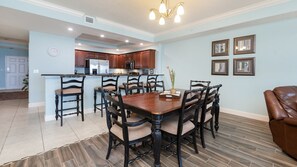 Una cocina amplia con armarios de madera oscura, una isla central y un comedor con una gran mesa y sillas de madera.