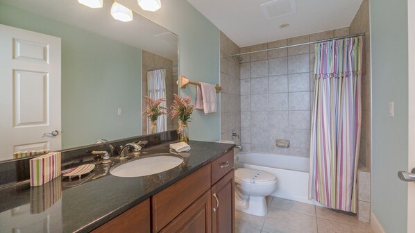 A bathroom with a sink, mirror, toilet, and shower.