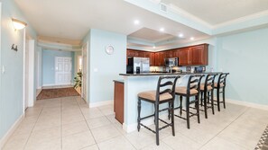 A kitchen with a central island, bar stools, and modern appliances. - 306 St Maarten - Oceanfront Paradise (Daytona Beach Shores)