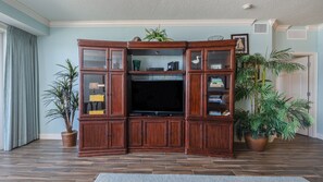 Una sala de estar con un mueble de madera para entretenimiento, un televisor de pantalla plana y varias plantas en macetas.