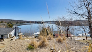 A lakeside view with a house, dock, and boats.
