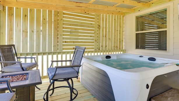 Un espace extérieur abrité comprenant un jacuzzi, une terrasse en bois et des sièges.