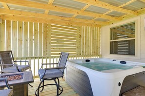 Un espacio al aire libre cubierto con un jacuzzi, una terraza de madera y asientos.