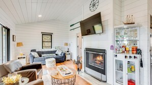 Una sala de estar con chimenea, un sofá, una mesa de centro y una estantería.