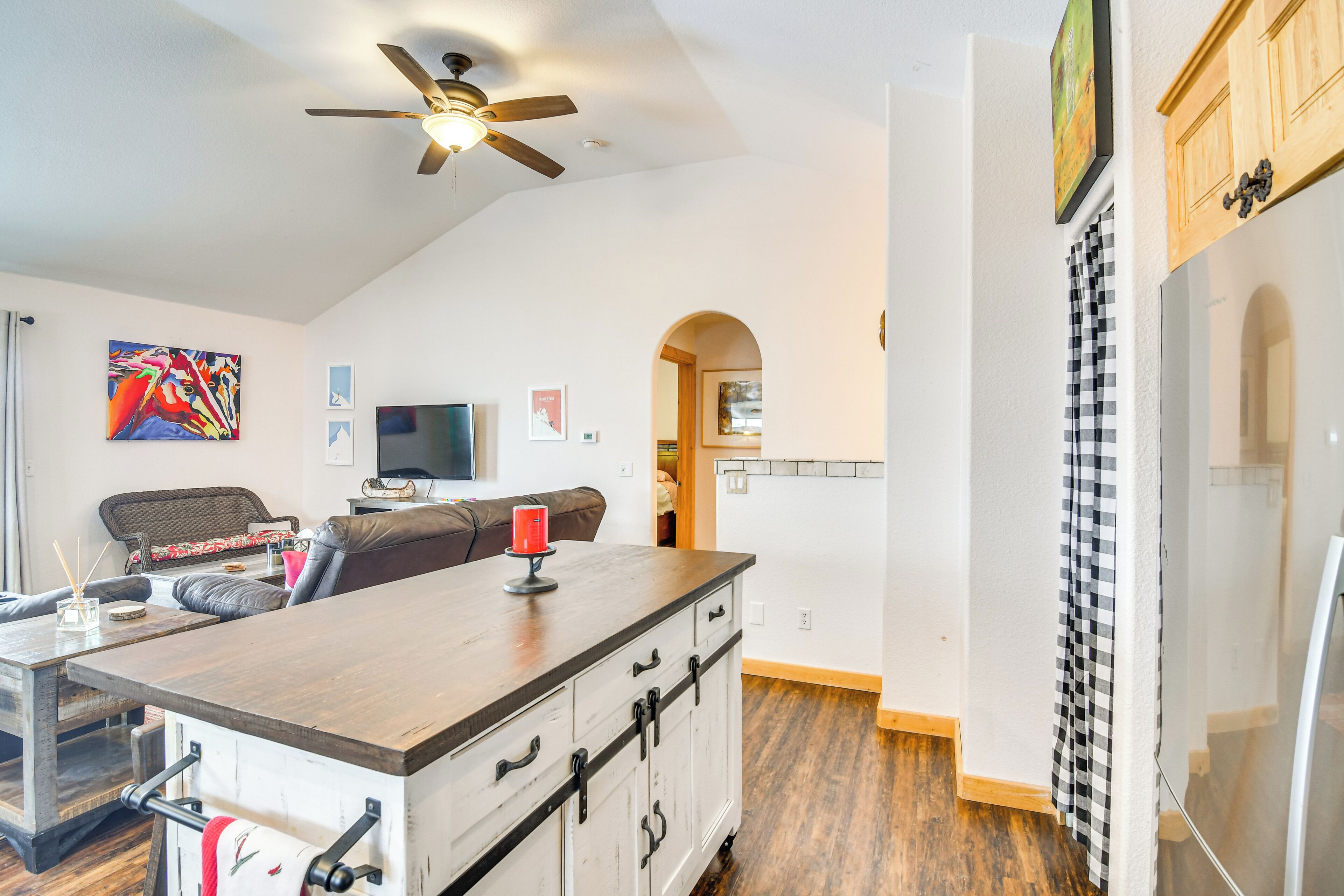 A modern kitchen with a wooden countertop, a ceiling fan, and a checkered towel hanging on the door.